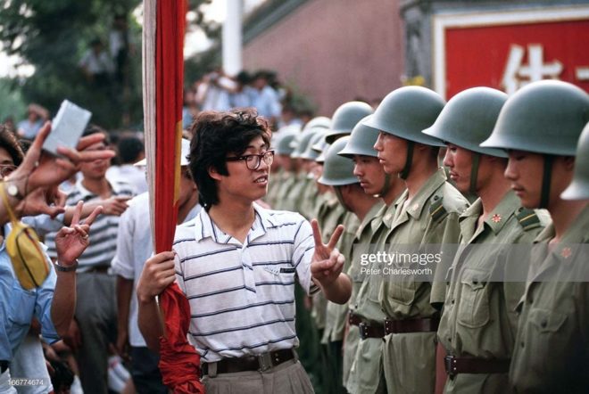 BEIJING, CHINA - 1989/06/01: A pro-democracy demonstrator gives the V for Victory sign to soldiers who are lined up, standing guard outside the Chinese Communist Party's headquarters on Chiangan Avenue just days before the bloody crackdown on students and protestors in and around Tiananmen Square.. (Photo by Peter Charlesworth/LightRocket via Getty Images)
