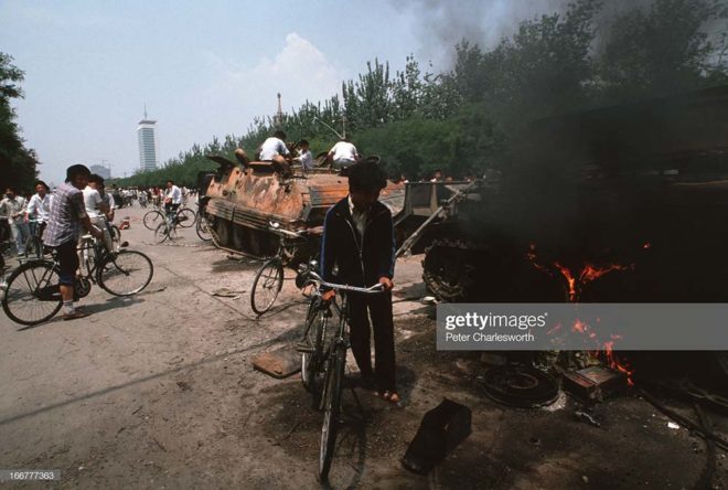 BEIJING, CHINA - 1989/06/04: At the end of the pro-democracy movement in China, onlookers examine Chinese Army trucks and vehicles that were damaged or destroyed during the night of violence in and around Tiananmen Square. After weeks of protesting, the Communist Government carried out its final brutal nighttime crackdown on protestors only hours before this picture was taken.. (Photo by Peter Charlesworth/LightRocket via Getty Images)