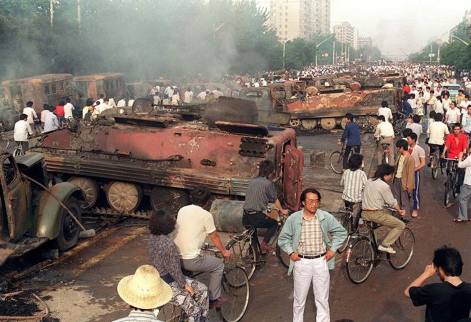 BEIJING, CHINA: Beijing residents inspect the interior of some of over 20 armoured personnel carrier burnt by demonstrators to prevent the troops from moving into Tiananmen Square 04 June 1989. On the night of 03 and 04 June 1989, Tiananmen Square sheltered the last pro-democracy supporters. Chinese troops forcibly marched on the square to end a weeks-long occupation by student protestors, using lethal force to remove opposition it encountered along the way. Hundreds of demonstrators were killed in the crackdown as tanks rolled into the environs of the square. (Photo credit should read MANUEL CENETA/AFP/Getty Images)