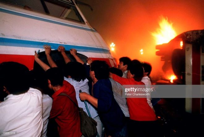 BEIJING, CHINA - 1989/06/04: Pro-democracy demonstrators overturn a bus in front of a burning truck on Changan Avenue in order to try and hold up soldiers who are fighting their way towards Tiananmen Square on the night of the Communist Government's bloody crackdown on students and protestors.. (Photo by Peter Charlesworth/LightRocket via Getty Images)
